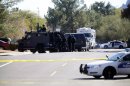 A SWAT team stands in position outside of a home of a suspected gunman who fired shots inside an office building during business hours in Phoenix