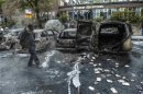 A bystander checks the debris around a row of burnt cars in the suburb of Rinkeby after youths rioted in several different suburbs around Stockholm