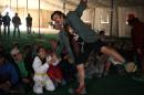 Moises Queralt, a clown from Mabsutins, a group of clowns from Spain, acts weak as a Syrian refugee child in a karate uniform pulls his arm during their show at Zaatari refugee camp near the Syrian border in Mafraq, Jordan, Sunday, Dec. 1, 2013. It was an unusual day for Syrian refugee children: Pinocchio and other show gigs live Sunday under a wind-swept tent in a sprawling desert camp straddling the Syrian border. (AP Photo/Mohammad Hannon)