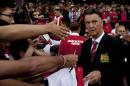 Manchester United's new manager Louis van Gaal, right, signs autographs as he takes to the touchline before his team's pre season friendly soccer match against Valencia at Old Trafford Stadium, Manchester, England, Tuesday Aug. 12, 2014. (AP Photo/Jon Super)