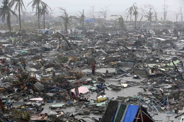 People stand among debris and ruins of houses destroyed after Super Typhoon Haiyan battered Tacloban city in central Philippines November 10, 2013. Haiyan, one of the most powerful storms ever recorded killed at least 10,000 people in the central Philippines province of Leyte, a senior police official said on Sunday, with coastal towns and the regional capital devastated by huge waves. Super typhoon Haiyan destroyed about 70 to 80 percent of the area in its path as it tore through the province on Friday, said chief superintendent Elmer Soria, a regional police director. REUTERS/Erik De Castro (PHILIPPINES - Tags: DISASTER ENVIRONMENT TPX IMAGES OF THE DAY)