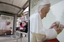 People walk by posters showing Pope Francis on September 20, 2014 in Tirana