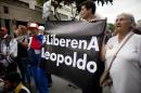 In this Nov. 18, 2014 photo, supporters of opposition leader Leopoldo Lopez hold a sign that reads in Spanish " Free Leopoldo," as they stand outside of the Palace of Justice during Lopez's trial in Caracas, Venezuela. Lopez has been in custody since February 2014 and is charged with inciting crimes during anti-government protests that raged through the winter and spring, leaving at least 43 people dead and hundreds injured. (AP Photo/Ariana Cubillos)