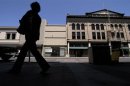 A woman walks past shuttered businesses in Stockton, California
