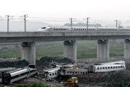 A bullet train passes over the wrecked carriages involved in Saturday's crash in Wenzhou, east China's Zhejiang Province, on Monday, July 25, 2011. The Chinese government on Tuesday ordered a two-month, nationwide safety campaign for its railway system after a collision between two bullet trains killed dozens of people. (AP Photo) CHINA OUT