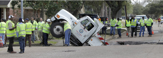City  crews work to attach chains on a City of Houston Public Works dump truck, after it fell into a sink hole caused by a cave-in on Balmforth at Dumfries near Godwin Park, Tuesday, Feb. 8, 2011, in H