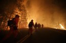 Inmate firefighters walk along Highway 120 as firefighters continue to battle the Rim Fire near Yosemite National Park, Calif., on Sunday, Aug. 25, 2013. Fire crews are clearing brush and setting sprinklers to protect two groves of giant sequoias as a massive week-old wildfire rages along the remote northwest edge of Yosemite National Park. (AP Photo/Jae C. Hong)