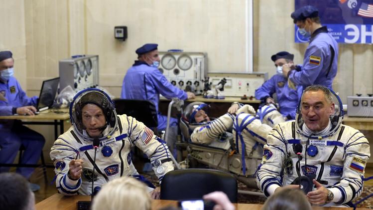 Members of the ISS crew, U.S. astronaut Swanson and Russian cosmonaut Skvortsov speak with relatives as Russian cosmonaut Artemyev tests a space suit during pre-launch preparations at the Baikonur cosmodrome