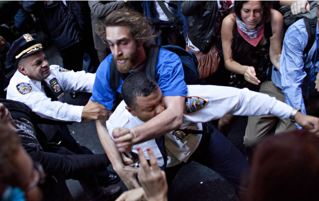 FILE - In this Oct. 14, 2011 file photo, a man affiliated with the Occupy Wall Street  protests tackles a police officer during a march towards Wall Street in New York. The official cleanup of a plaza