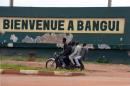 A motorcycle taxi drives past a sign reading "Welcome to Bangui" near the Bangui airport, on May 1, 2014