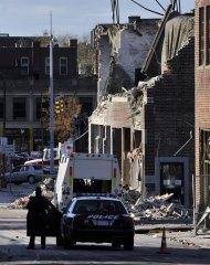 People keep a perimeter, Saturday, Nov. 24, 2012, around the area where a gas explosion leveled a strip club in Springfield, Mass., on Friday evening. Investigators were trying to figure out what caused the blast where the multistory brick building housing Scores Gentleman's Club once stood. (AP Photo/Jessica Hill)