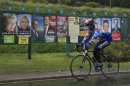 Cyclist rides past electoral panels with campaign posters of candidates for 2012 French presidential election, in Mons en Pevele near Lille