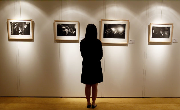 A Christie's employee looks at Mike Mitchell's photographs of The Beatles where his collection is being exhibited at a hotel in London, Friday, June 10, 2011. The previously unseen photographs by US p