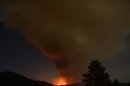 A plume of smoke rises into the night sky as a wildfire, or the so-called Mountain Fire, burns near Idyllwild