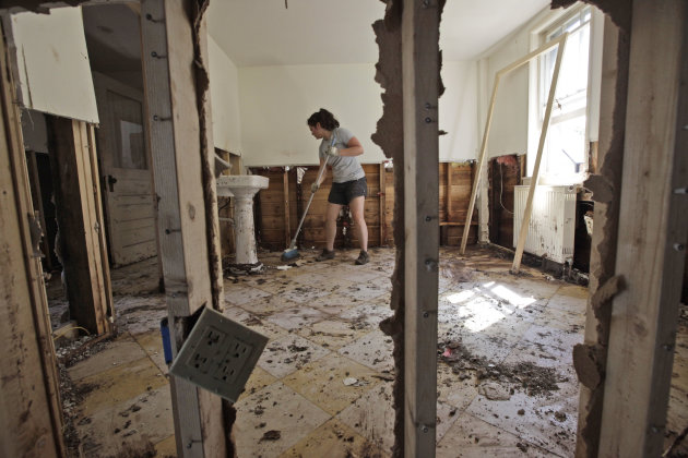 Meghan Morrow sweeps mud and debris from what is left of the Windham Spa, Tuesday, Aug. 30, 2011 in Windham, N.Y. Officials say more than a dozen towns in Vermont and at least three in New York are cu