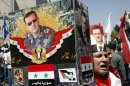 A supporter of Syria's President Bashar al-Assad holds pictures of him and his father in Damascus