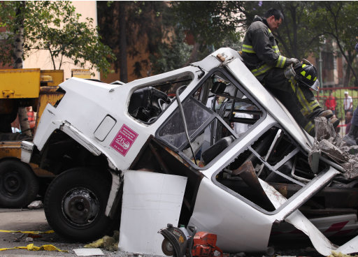 A firefighter leans against the roof of a damaged mini-bus while standing on the beam that fell from a bridge onto the bus during an earthquake, in Mexico City, Tuesday March 20, 2012. A strong 7.4-magnitude earthquake hit central and southern Mexico on Tuesday, collapsing at least 60 homes near the epicenter and a pedestrian bridge in the capital where people fled shaking office buildings. There were no passengers in the mini-bus and the driver suffered minor injuries, according to firefighters. (AP Photo/Alexandre Meneghini)