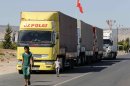 Locals walk past trucks lined up at the Oncupinar border crossing on the Turkish-Syrian border in Kilis