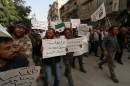 Supporters of Al-Qaeda's Syria affiliate Al-Nusra Front hold placards calling Syrian President Bashar al-Assad a "terrorist", as they demonstrate in the northern city of Alepppo on September 24, 2014