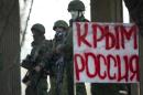 Unidentified gunmen wearing camouflage uniforms block the entrance of the Crimean Parliament building in Simferopol, Ukraine, Saturday, March 1, 2014. The discord between Russia and Ukraine sharpened Saturday when the pro-Russian leader of Ukraine's Crimea region claimed control of the military and police and appealed to Russia's president for help in keeping peace there. Poster reads "Crimea Russia". (AP Photo/Ivan Sekretarev)