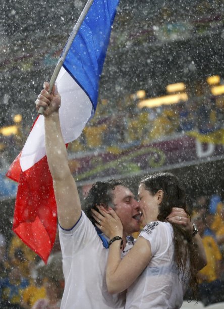 French fans kiss in the rain after their Group D Euro 2012 soccer match against Ukraine was suspended at the Donbass Arena in Donetsk