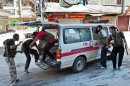 Syrian rebel fighters load a wounded person into an ambulance during clashes with Syrian government forces in Aleppo