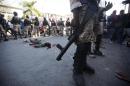 The National Police stand around the body of Neroce R. Ciceron, a former captain in Haiti's disbanded army, after he was beaten and stoned to death by anti-government protesters in Port-au-Prince, Haiti, Friday, Feb. 5, 2016. Members of Haiti's abolished military clashed with protesters who were demanding the resignation of president Michel Martelly. Some protesters hurled rocks at the ex-soldiers, and a few ex-soldiers fired their weapons. Haiti's military was abolished in 1995 because of its history of toppling governments and crushing dissent. (AP Photo/Dieu Nalio Chery)