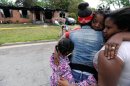 Sisters Brandy McCrary, left, and Breona Montgomery, who are cousins of the five fatal house fire victims, hug neighbors Bonita Beasley, center, and Jennifer Moss, right, in Newnan, Ga., Saturday, April 27, 2013. The fire killed Alonna T. McCrary, 27, as well as her 5-year-old daughter Eriel McCrary and 2-year-old daughter Nikia White, according to Glenn Allen, the Georgia state Insurance commissioner's spokesman. Two other children, Messiah White, 3, and McKenzie Florence, 2, also died. Allen said the two were sleeping over at the home. A fifth child, 11-year-old Nautica McCrary, escaped the burning home and was taken to a hospital to be treated for smoke inhalation. (AP Photo/David Tulis)