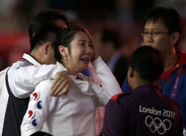 South Korea's Shin reacts as she is escorted after being defeated by Germany's Heidemann during their women's epee individual semifinal fencing competition at the ExCel venue at the London 2012 Olympi