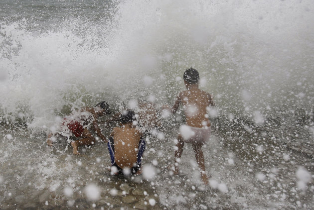 Filipino boys play amid strong waves at Manila bay, Philippines, Sunday, Aug. 28, 2011. Slow-moving Typhoon Nanmadol remained dangerous Sunday despite weakening as it struck the tip of the mountainous