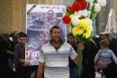 Ghaith Ismail, center, holds flowers during the funeral procession for his brother, Layth Ismail, in the Shiite holy city of Najaf, 100 miles (160 kilometers) south of Baghdad, Iraq, Thursday, March 6, 2014. Ismail, an Iraqi soldier, was killed during clashes with al-Qaida-led militants in Ramadi. (AP Photo/Jaber al-Helo)