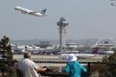 People watch as a United Airlines jet passes the air traffic control tower at Los Angeles International Airport (LAX) during take-off on April 22, 2013