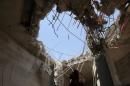 A man looks at a hole caused by a Saudi-led air strike on a building in the northwestern city of Saada