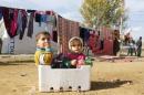 Syrian refugee children sit in a box at a makeshift settlement in Qab Elias in the Bekaa valley