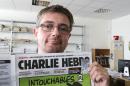 In this Sept.19, 2012 file photo, Stephane Charbonnier also known as Charb , the publishing director of the satyric weekly Charlie Hebdo, displays the front page of the newspaper as he poses for photographers in Paris. Masked gunmen shouting 