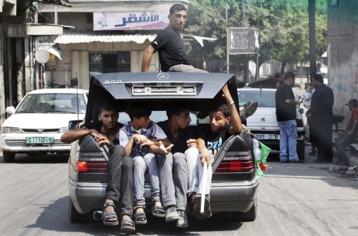 Palestinians sit in the boot of a car as they follow the convoy of released Palestinian soccer player Al-Sarsak upon his arrival in Gaza