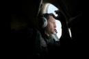 In this Monday, March 24, 2014 photo, a crew member of an Royal Australian Air Force AP-3C Orion patrol plane, looks out of his observation window whilst searching for the missing Malaysia Airlines Flight MH370 over the Indian Ocean. They lean forward as far as they can, occasionally pressing their foreheads against the plane's windows so hard they leave grease marks, staring out at a punishingly unbroken expanse of gray water that seems, at times, to blend into the clouds. Their eyes dart up and down, left and right, looking for something - anything - that could explain the fate of the missing Malaysia Airlines plane. (AP Photo/Richard Wainwright, Pool, File)