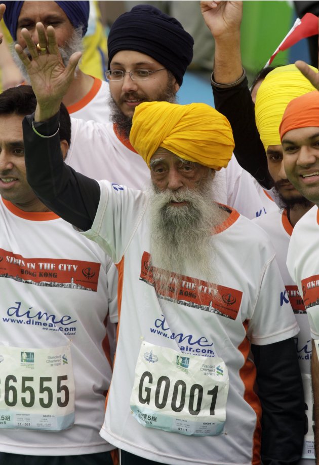 British Indian marathon runner Fauja Singh, 101, waves to fans after finishing the 10-kilometer race of the Hong Kong Marathon