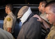An unidentified person (C) is escorted out of Nakoula Basseley Nakoula's home by Los Angeles County Sheriff's officers in Cerritos, California September 15, 2012.  Nakoula, a California man convicted of bank fraud is under investigation for possible probation violations stemming from the making of an anti-Islam video that has  triggered violent protests against the U.S.in the Muslim world, U.S. officials said on Friday. REUTERS/Bret Hartman
