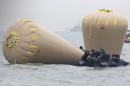 South Korean navy personnel try to install buoys to mark the sunken passenger ship Sewol in the water off the southern coast near Jindo, South Korea, Friday, April 18, 2014. Rescuers scrambled to find hundreds of ferry passengers still missing Friday and feared dead, as fresh questions emerged about whether quicker action by the captain of the doomed ship could have saved lives. (AP Photo/Yonhap) KOREA OUT