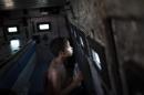 A young resident looks through a small bullet proof window as he sits inside a police armored vehicle after a police operation to occupy the Vila Pinheiro, part of the Mare slum complex in Rio de Janeiro, Brazil, Sunday, March 30, 2014. The Mare complex of slums, home to about 130,000 people and located near the international airport, is the latest area targeted for the government's "pacification" program, which sees officers move in, push out drug gangs and set up permanent police posts. (AP Photo/Felipe Dana)