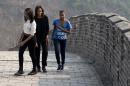 FILE - This March 23, 2014 file photo shows first lady Michelle Obama walking with her daughters Malia, left, and Sasha, right, as they visit the Mutianyu section of the Great Wall of China in Beijing. When President Barack Obama travels abroad, getting just the leader of the free world doesn't seem to be enough. Countries want the first lady, too. But Michelle Obama won't join her husband when he heads to Asia next week and her absence is likely to sting, especially in Japan. It's the first of four countries on Obama's travel schedule and the only one welcoming him on an official state visit. (AP Photo/Andy Wong, File)