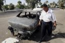 FILE - This Sept. 25, 2007 file photo shows an Iraqi traffic policeman inspects a car destroyed by a Blackwater security detail in al-Nisoor Square in Baghdad, Iraq. After years of delays, four former guards from the security firm Blackwater Worldwide are facing trial in the killings of 14 Iraqi civilians and the wounding of 18 others in bloodshed that inflamed anti-American sentiment around the globe. Whether the shootings were self-defense or an unprovoked attack, the carnage of Sept. 16, 2007 was seen by critics of the George W. Bush administration as an illustration of a war gone horribly wrong. A trial in the nearly 7-year-old case is scheduled to begin with jury selection on Wednesday, barring last-minute legal developments. (AP Photo/Khalid Mohammed, File)