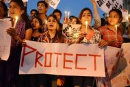 Jovens indianos seguram velas e cartazes em uma vigília após o estupro coletivo de uma estudante em Ahmedabad.