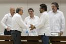 Humberto de la Calle, front left, head of Colombia's government peace negotiation team, shakes hands with Ivan Marquez, chief negotiator of the Revolutionary Armed Forces of Colombia (FARC), after signing an agreement on how to address the needs of 6 million victims, at Convention Palace in Havana, Cuba, Tuesday, Dec. 15, 2015. With Monday's announcement, there's a single unsettled issue: How members of the FARC will demobilize in order for both sides to reach a final deal. At center is Cuba's Foreign Minister Bruno Rodriguez. At far right and left are guarantors Rodolfo Benitez, from Cuba, and Dag Nylander, from Norway. (AP Photo/Ramon Espinosa)
