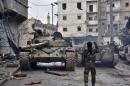 A member of the Syrian pro-government forces gestures to tanks as they patrol the northern embattled city of Aleppo on December 14, 2016