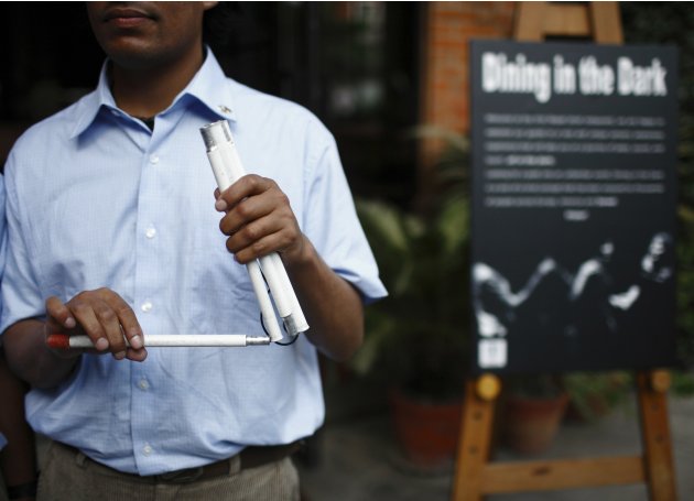 A visually impaired waiter arranges his walking stick as he waits for customers outside Nepal&#39;s first blind restaurant in Kathmandu