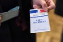 A woman presents her voting card during the first round of the regional elections in the Rhone-Alpes-Auvergne region on December 6, 2015 at a polling station in Limonest