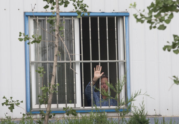 <p> American Chip Starnes, co-owner of Specialty Medical Supplies, waves from a window after he was held hostage by workers inside his plant at the Jinyurui Science and Technology Park in Qiao Zi township of Huairou District, on the outskirts of Beijing, China Monday, June 24, 2013. An American executive said Monday Starnes has been held hostage for four days at his medical supply plant in Beijing by dozens of workers demanding severance packages like those given to co-workers in a phased-out department. (AP Photo/Andy Wong)