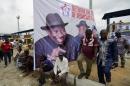 Supporters walk past a poster of the Nigerian President and presidential candidate of the ruling People's Democratic Party Goodluck Jonathan during an election rally in Port Harcourt on January 28, 2015